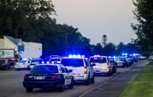 Lafayette Police Department and Louisiana State Police units block an entrance road following a shooting at The Grand Theatre in Lafayette, La., Thursday, July 23, 2015. (Paul Kieu/The Daily Advertiser via AP)